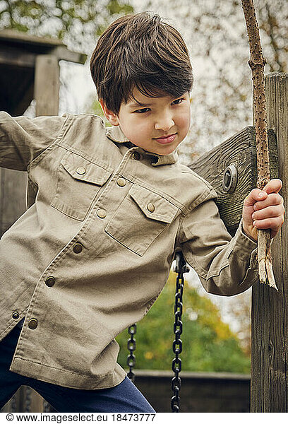 Boy holding plant stick at park
