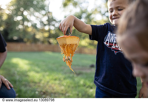 Boy holding pumpkin stem while standing in yard during Halloween