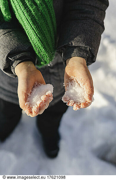 Boy holding snow in winter