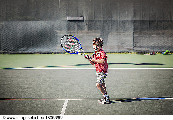 Boy holding tennis racket while standing at court