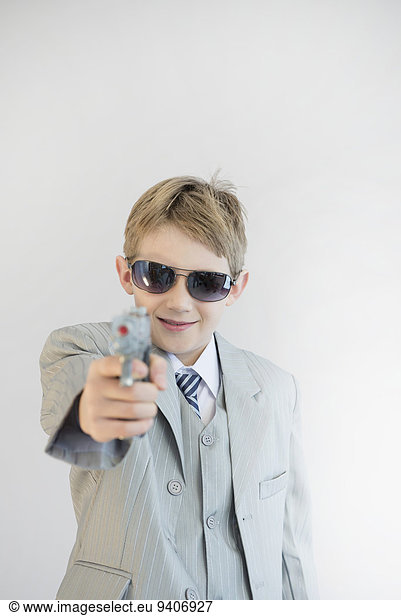 Boy holding toy gun and playing gangster  smiling