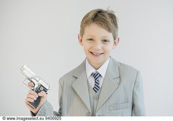 Boy holding toy gun and playing gangster  smiling  portrait