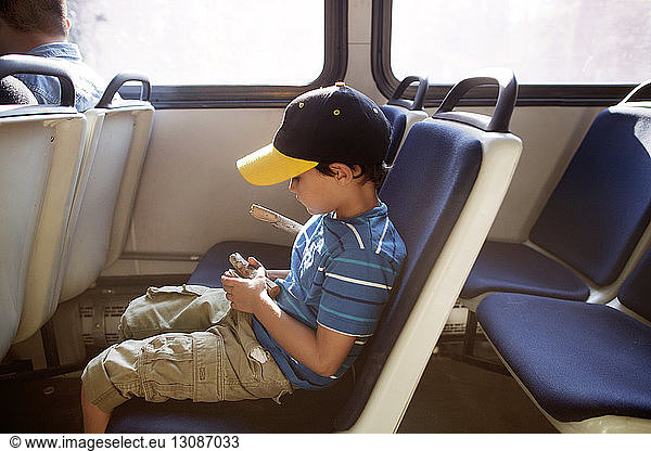 Boy holding wood and sitting on seat while travelling in train