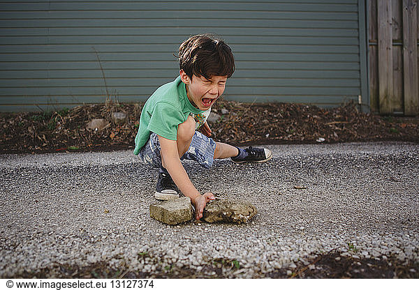 Boy imitating to break stones while practicing karate on street