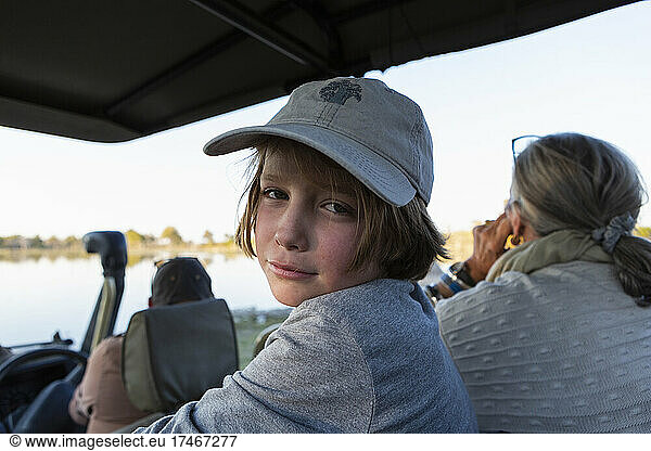 Boy in a safari jeep in a baseball cap looking at the camera