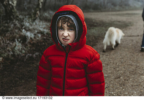 Boy in red winter coat looking at camera and snarling curling up nose