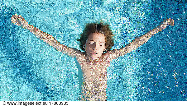 Boy in swimming pool with closed eyes  top down view