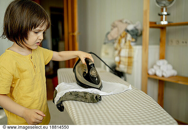Boy ironing clothes at home