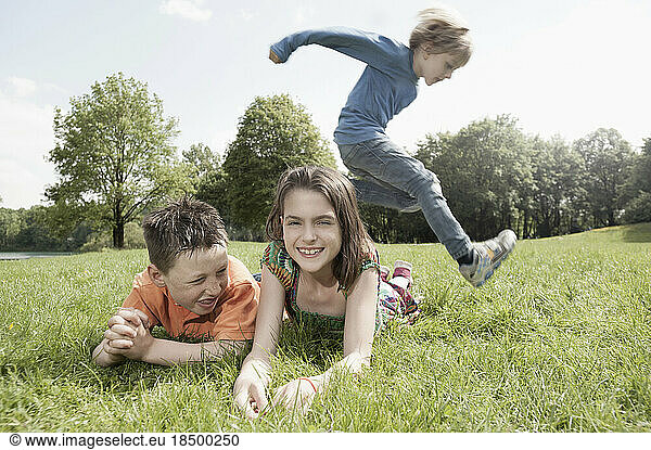Boy jumping over his friends lying on grass in a park  Munich  Bavaria  Germany