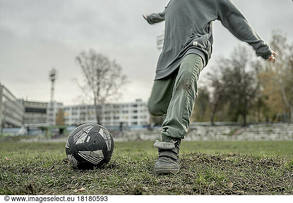 Boy kicking soccer ball at sports field