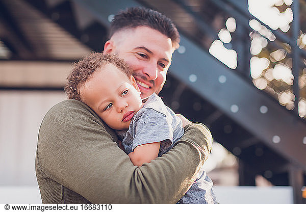 Boy leaning on dad's shoulder while dad smiles