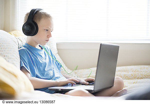 Boy listening music while using laptop computer at home