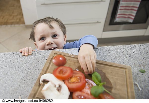 Boy looking at chopped vegetables in kitchen