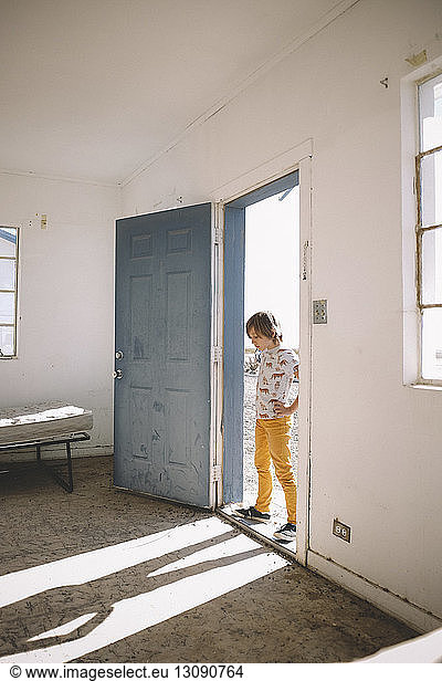 Boy looking at shadow while standing on doorway