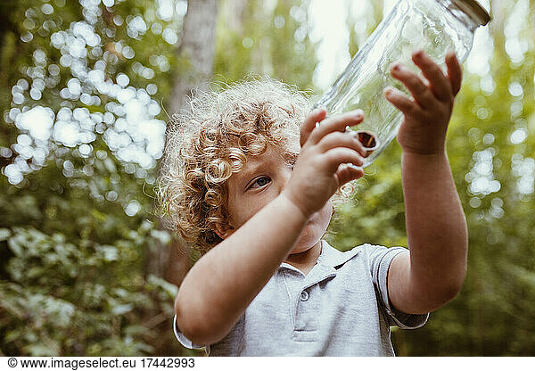 Boy looking at snails in glass jar