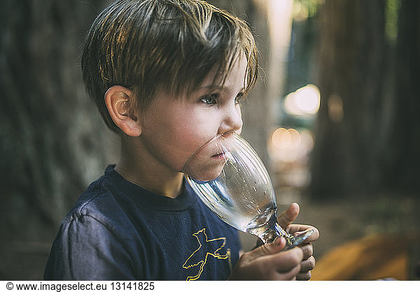 Boy looking away while playing with drinking glass