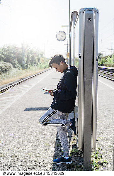 Boy looking his tablet in a train station