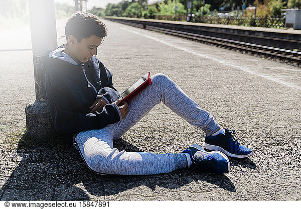 Boy looking his tablet in a train station