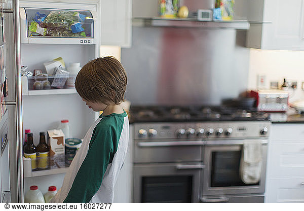 Boy looking inside kitchen refrigerator