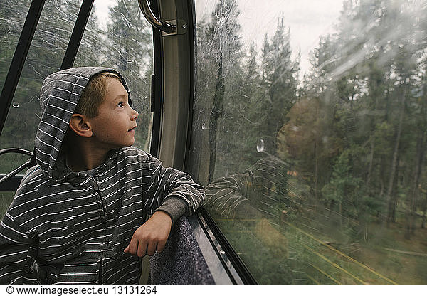 Boy looking through window while traveling in overhead cable car