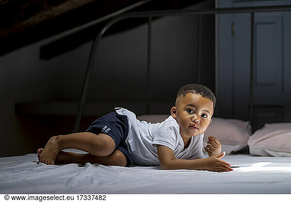 Boy lying on bed in attic at home