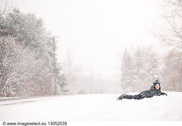 Boy lying on snow in winter landscape