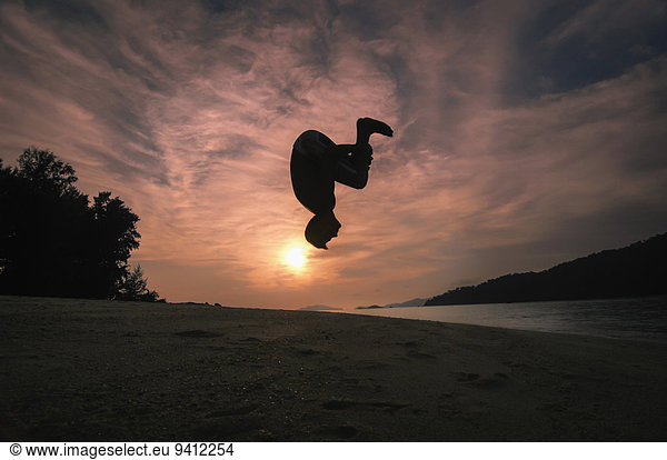 boy making backward roll at sunset  Koh Lipe  Thailand