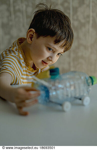 Boy making car from plastic bottle at home