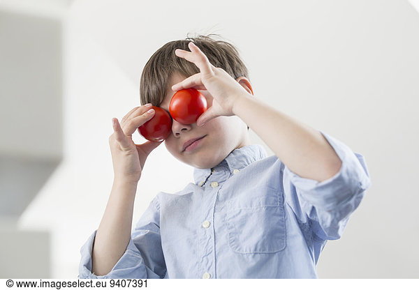 Boy making faces with tomatoes