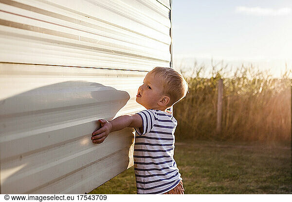 Boy (18-23 months) outside caravan in field