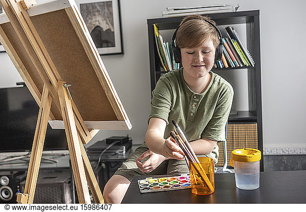 Boy painting at easel and listening to music