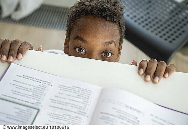 Boy peeking over the edge of table at home