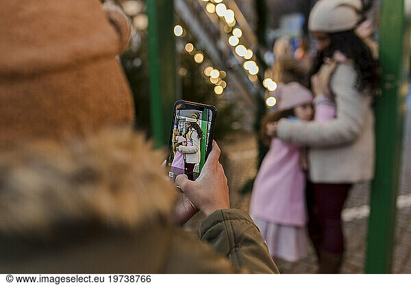 Boy photographing mother and sister through smart phone