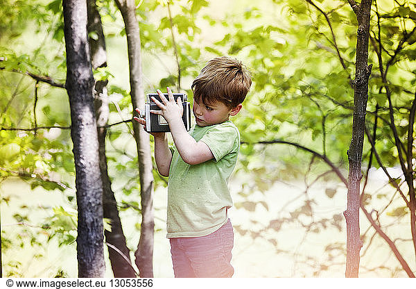 Boy photographing through vintage camera at park