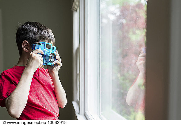 Boy photographing window while standing at home