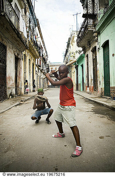 Boy playing baseball in street with broomstick bat  Havana  Cuba.