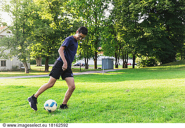 Boy playing football on grass in lawn