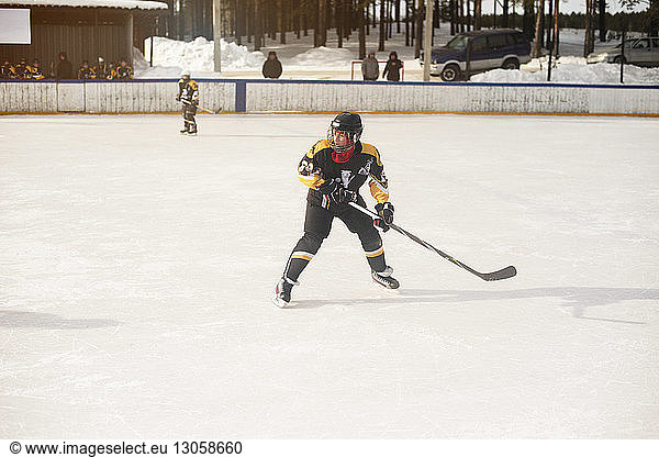 Boy playing ice hockey during sunny day
