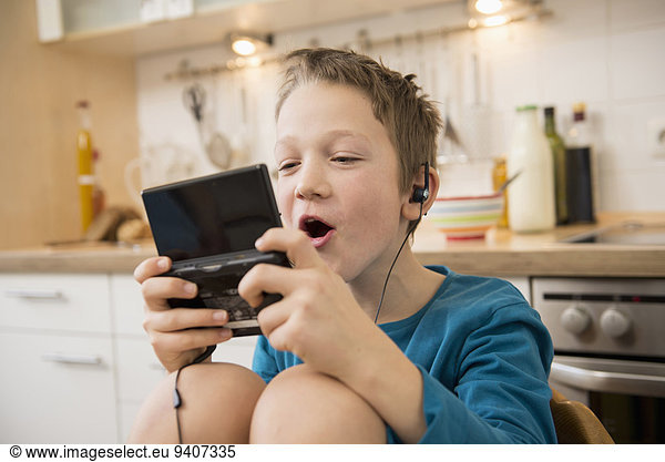 Boy playing video game in kitchen