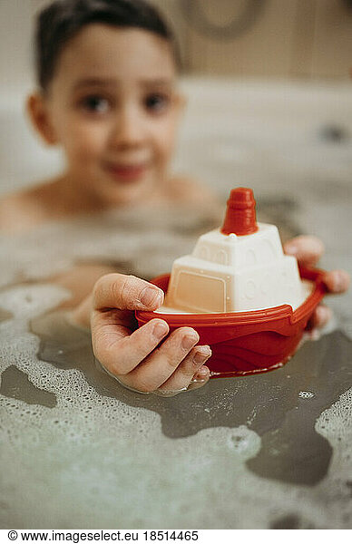 Boy playing with boat toy in bathtub