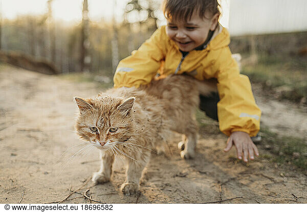 Boy playing with cat in forest