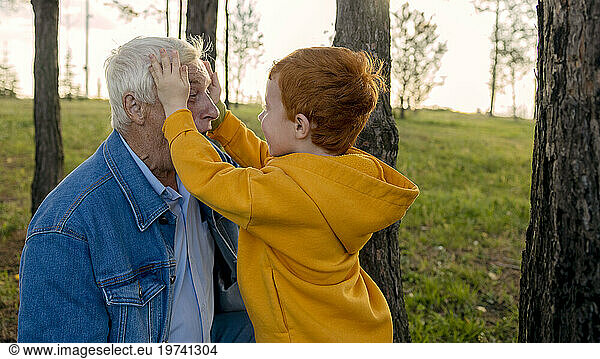 Boy playing with grandfather in park