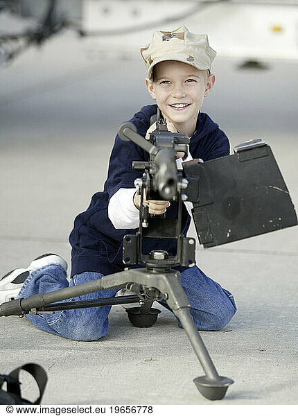Boy playing with machine gun on display.