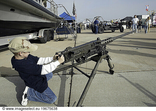 Boy playing with machine gun on display.
