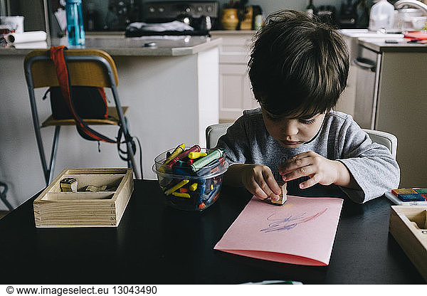 Boy playing with rubber stamp at home