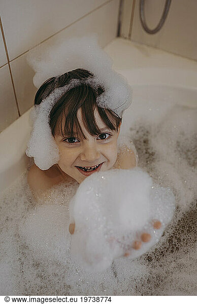 Boy playing with soap sud in bathtub at home