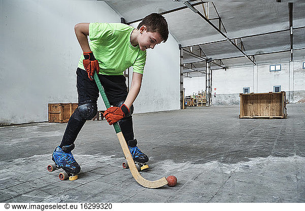 Boy practicing roller hockey during training at court