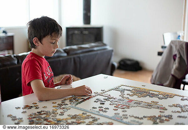 Boy putting puzzle together at kitchen counter