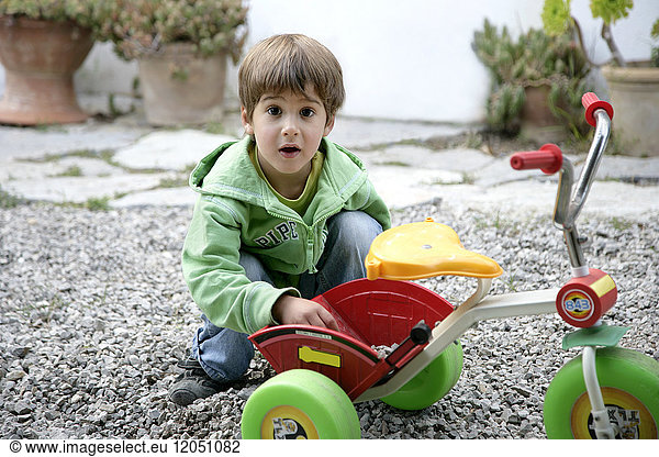 Boy Putting Small Stones in Tricycle