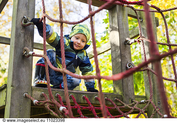 Boy ready to enter rope net during obstacle course in forest